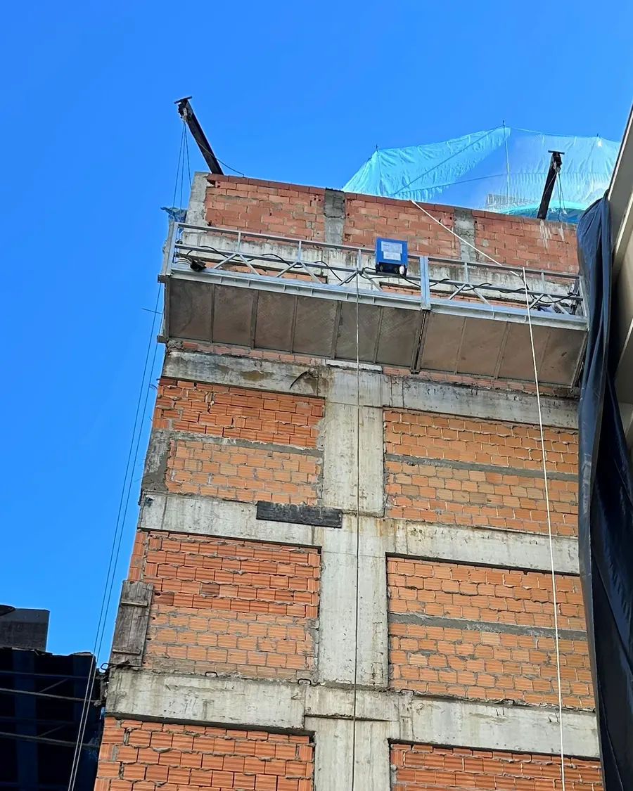 Fachada em alvenaria de um edifício em execução, vista do térreo, com balancim no topo