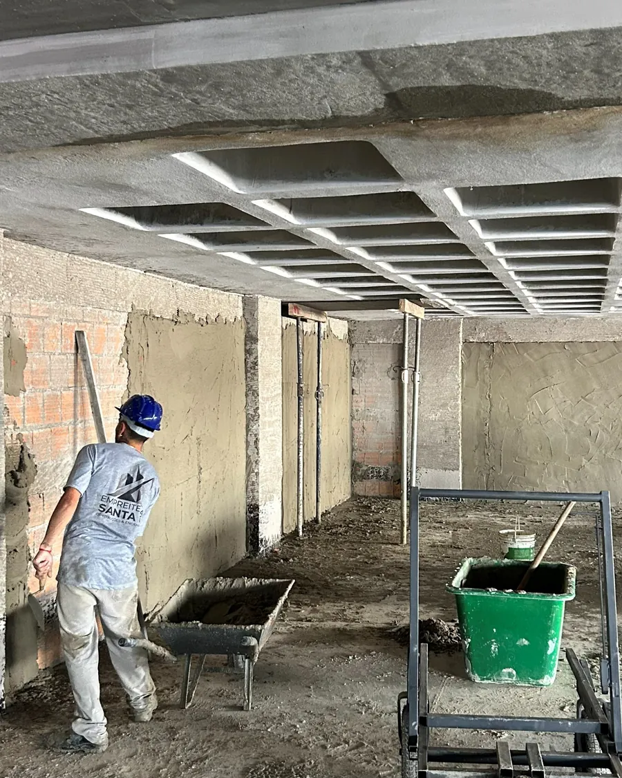 Colaborador aplicando reboco interno com desempenadeira